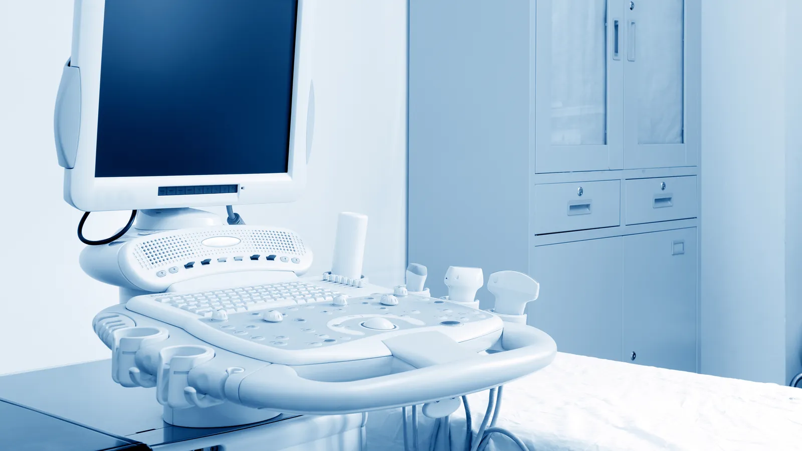 Ultrasound equipment beside an empty examination bed.